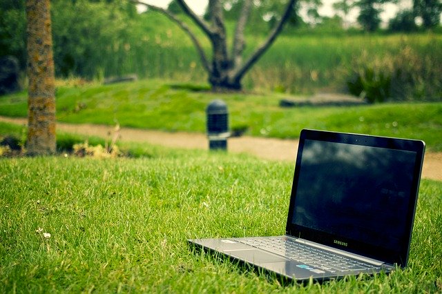 Tmavý notebook položený  na zelenom pokosenom trávniku.jpg