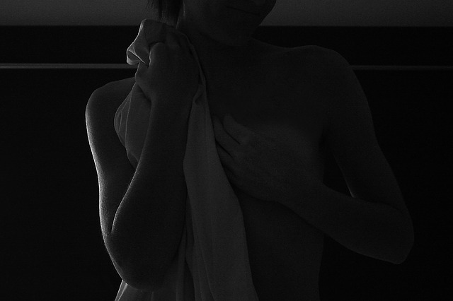 Čiernobiela fotografie nahej ženy, ktorá si zakrýva prsia.jpg